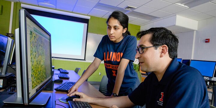 A female undergraduate student in crop sciences and an instructor discuss a class assignment while looking at a computer screen.