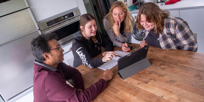 Professor assisting students on an iPad