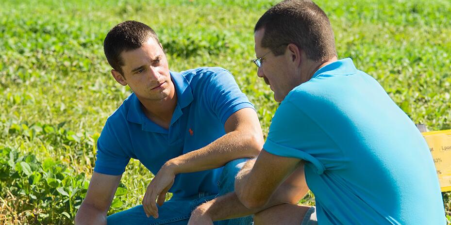 Student working with a professor in a field